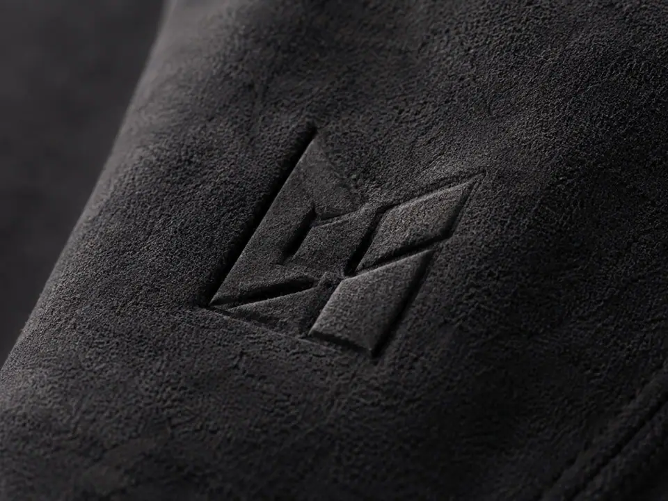 Emblem embossed directly into dark suede-textured cloth