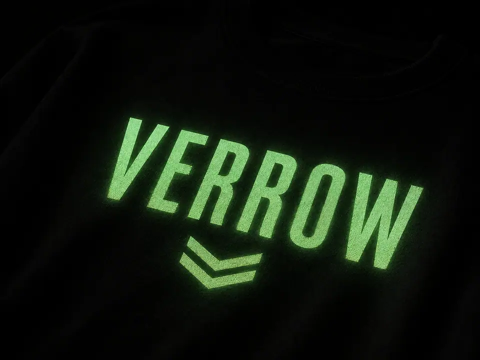 A glow-in-the-dark print emitting soft pale green light on a black cotton panel photographed in a darkened studio.