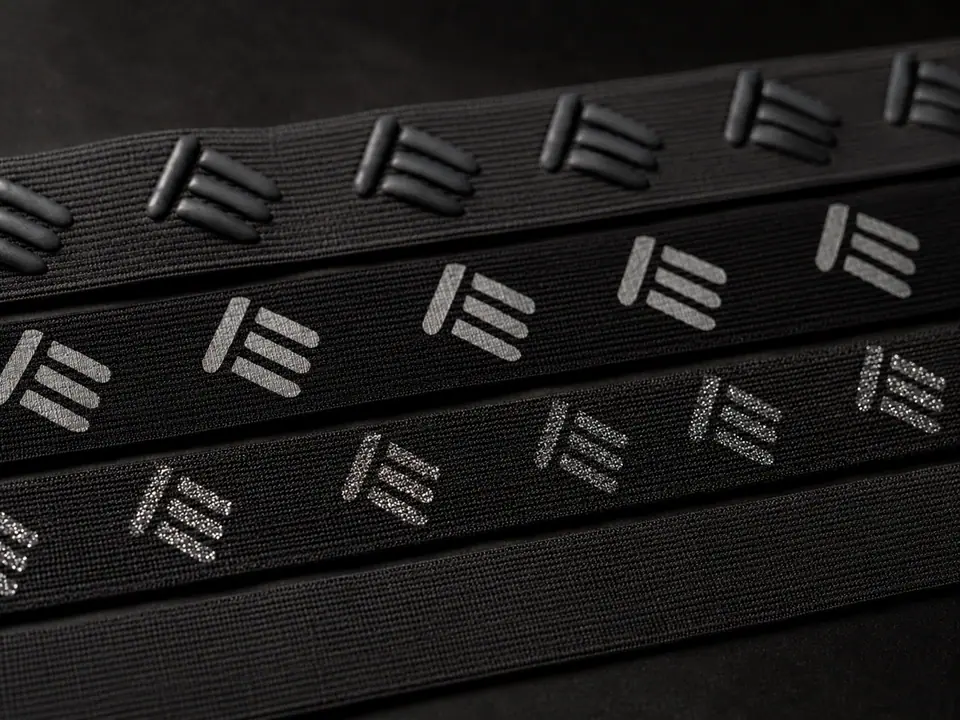 Printed elastic waistband tapes carrying repeated motifs in raised, flat and glitter finishes