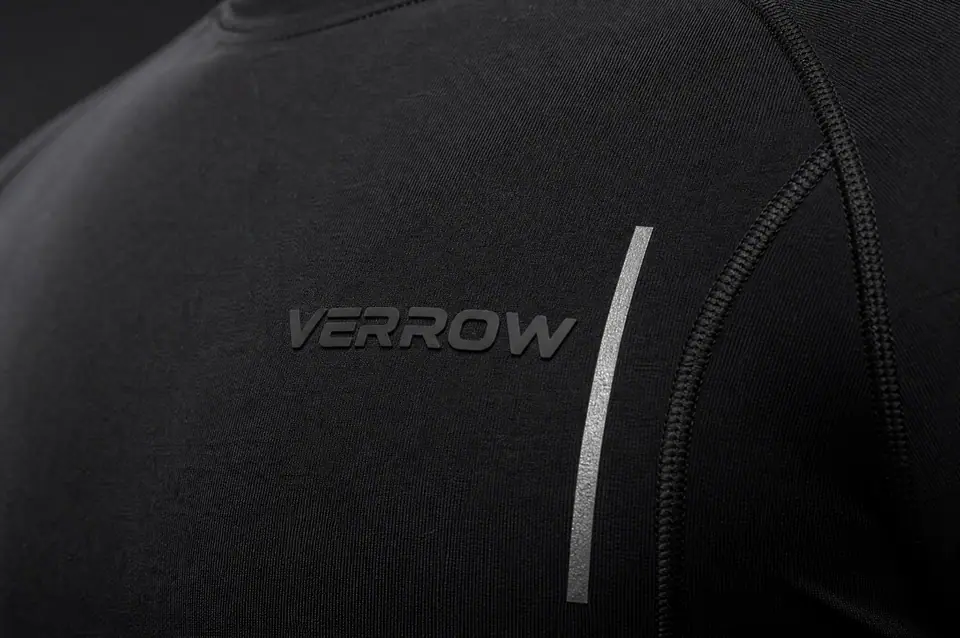 Macro of a black technical training top: a tonal matte silicone VERROW logo raised on the knit beside a narrow reflective stripe